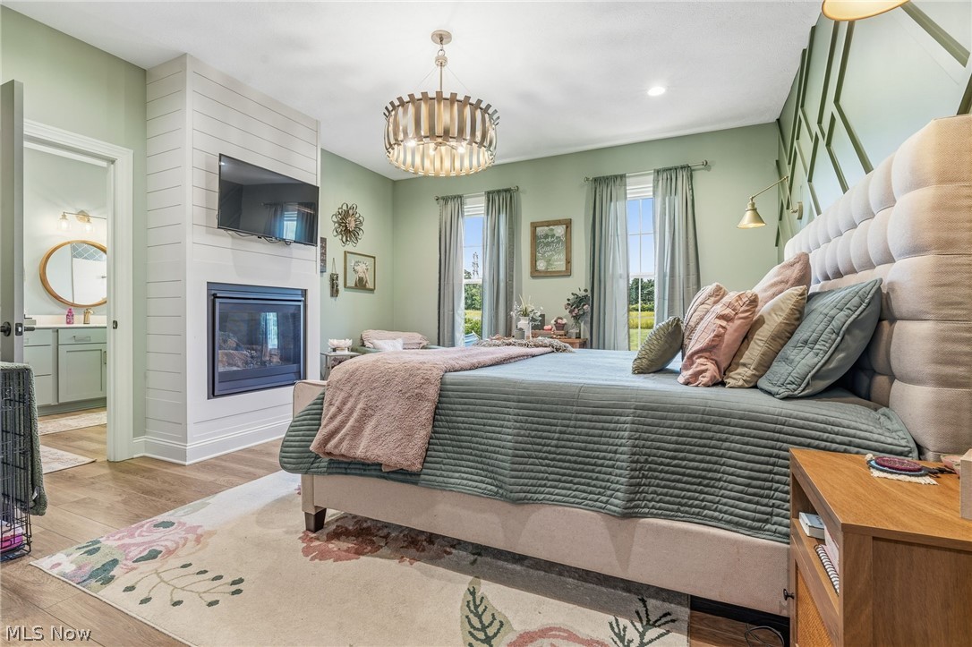 421 Pontius Road Mogadore, OH 44260 - Photo 12 of 50 Wood-finish flooring, shiplap fireplace surround, built-in electric fireplace, geometric accent wall, and a drum-style chandelier