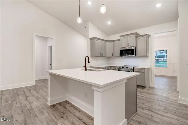 a kitchen with kitchen island a sink a stove a microwave and wooden floor