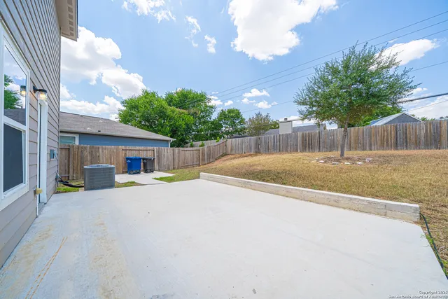 a view of backyard of house with wooden fence