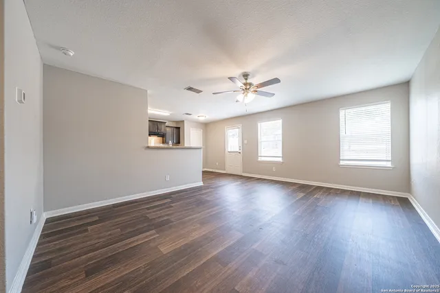a view of an empty room with a window and wooden floor