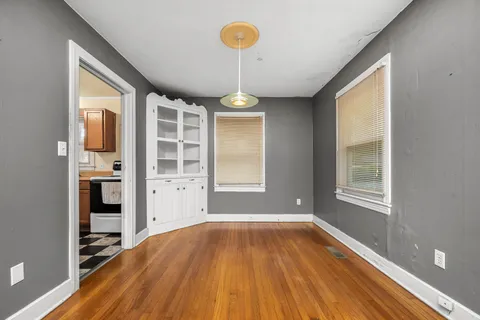 a view of a room with wooden floor chandeliers and kitchen view