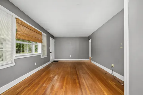 a view of an empty room with wooden floor and a window