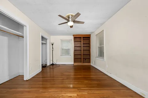 a view of empty room with wooden floor and window