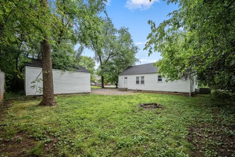 a backyard of a house with plants and a large tree