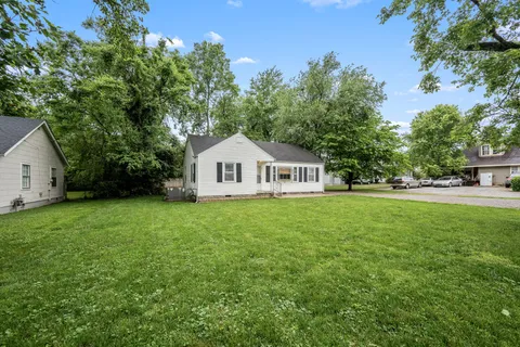 a view of a white house with a yard and sitting area