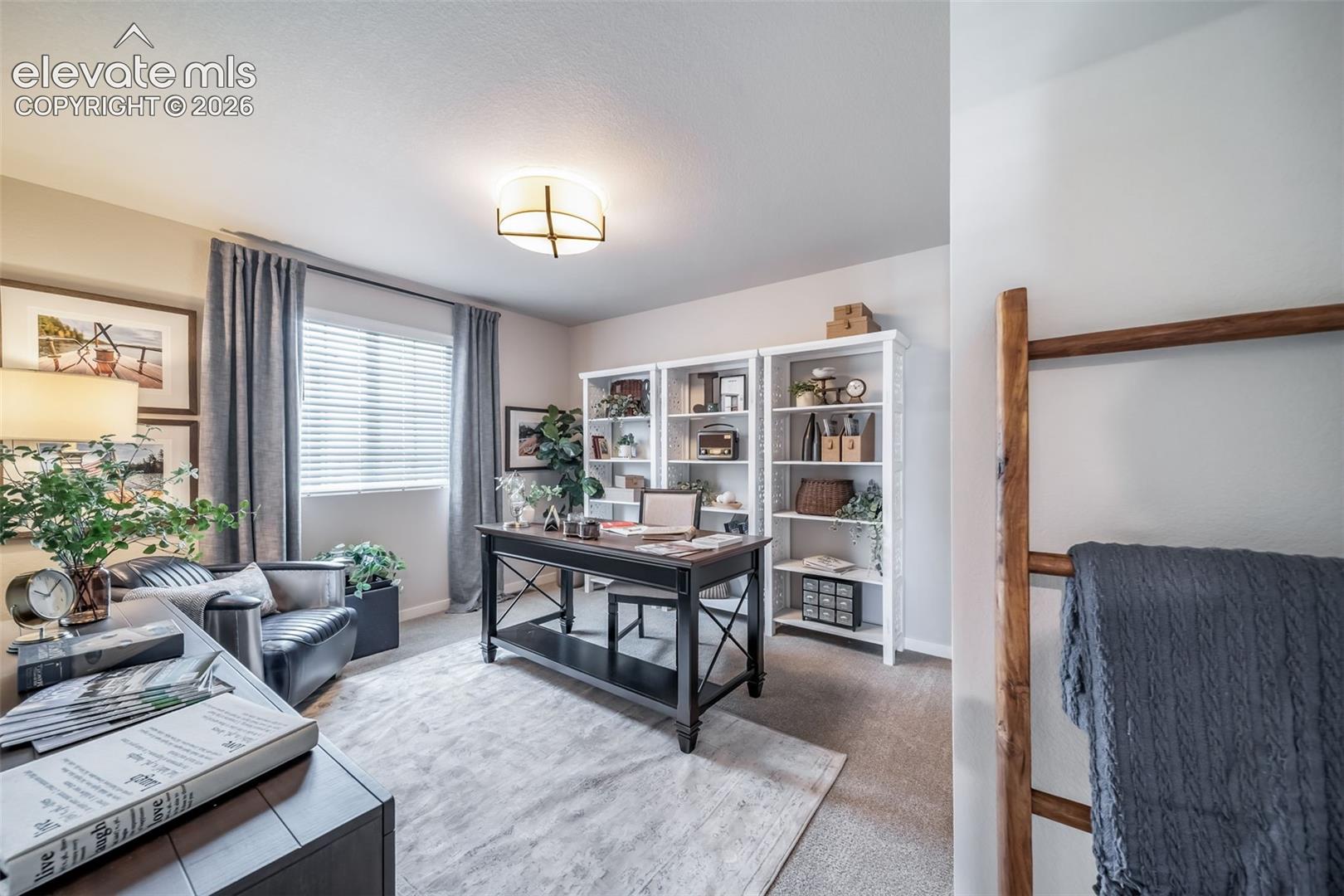 4876 Truscott Road Colorado Springs, CO 80925 - Photo 9 of 28 Dedicated office space featuring two built-in shelving units, a large window with blinds, overhead lighting, and carpet flooring
*Photos of a model home*