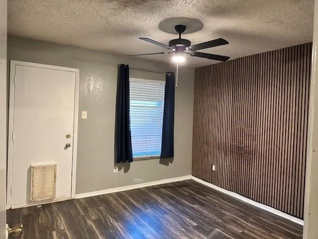 an empty room with wooden floor chandelier fan and windows