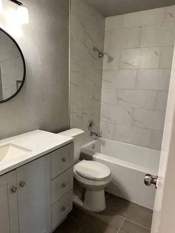 a bathroom with a granite countertop toilet a sink and bathtub