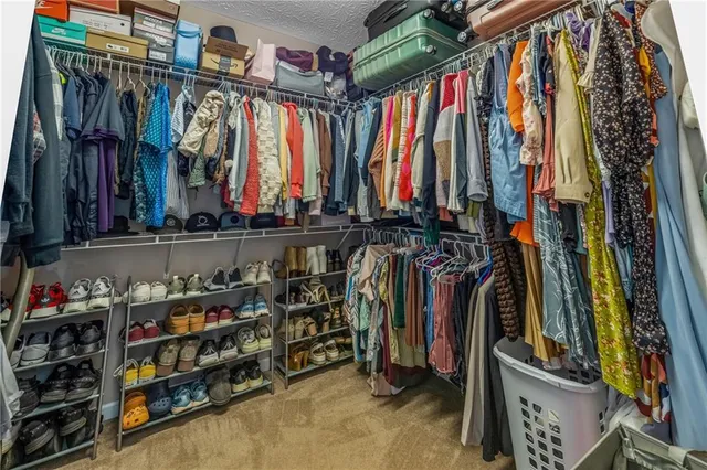 a view of walk in closet with clothes and shoes