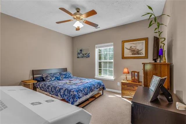 a bedroom with a bed a computer on a desk and a book shelf