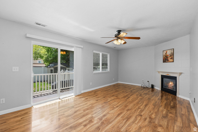 142 East 2675th Street South Clearfield, UT 84015 - Photo 14 of 49 Spacious room featuring wood-finish flooring, a ceiling fan with integrated lighting, and a corner fireplace with a mantel