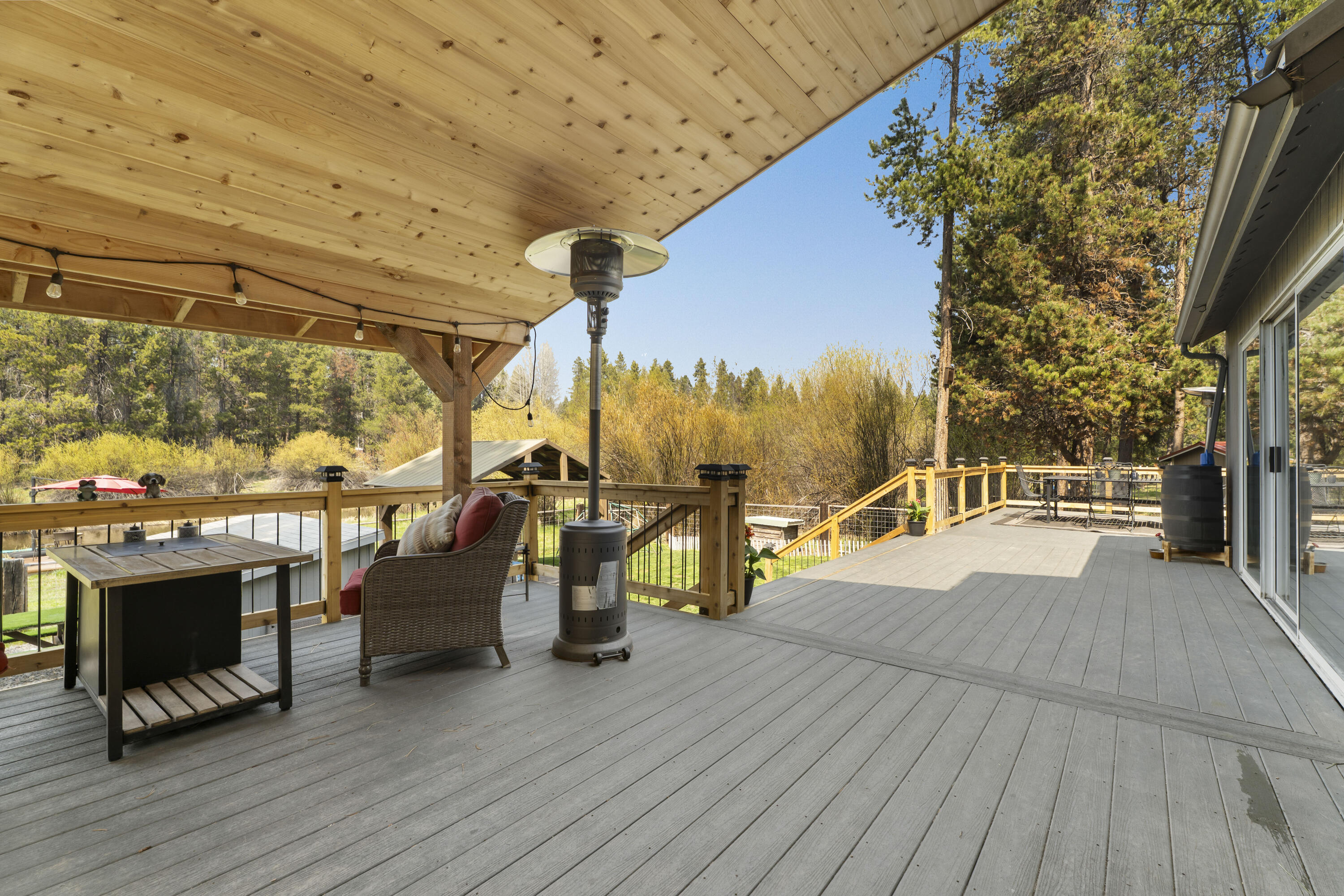 17062 Milky Way Bend, OR 97707 - Photo 20 of 39 Covered deck with patio heater and string lights framed by towering pines