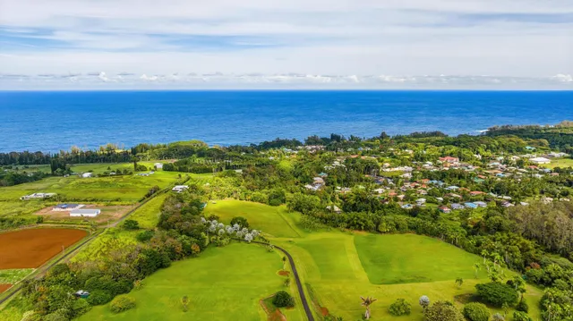 a white house with a large pool and lawn chairs under an umbrella