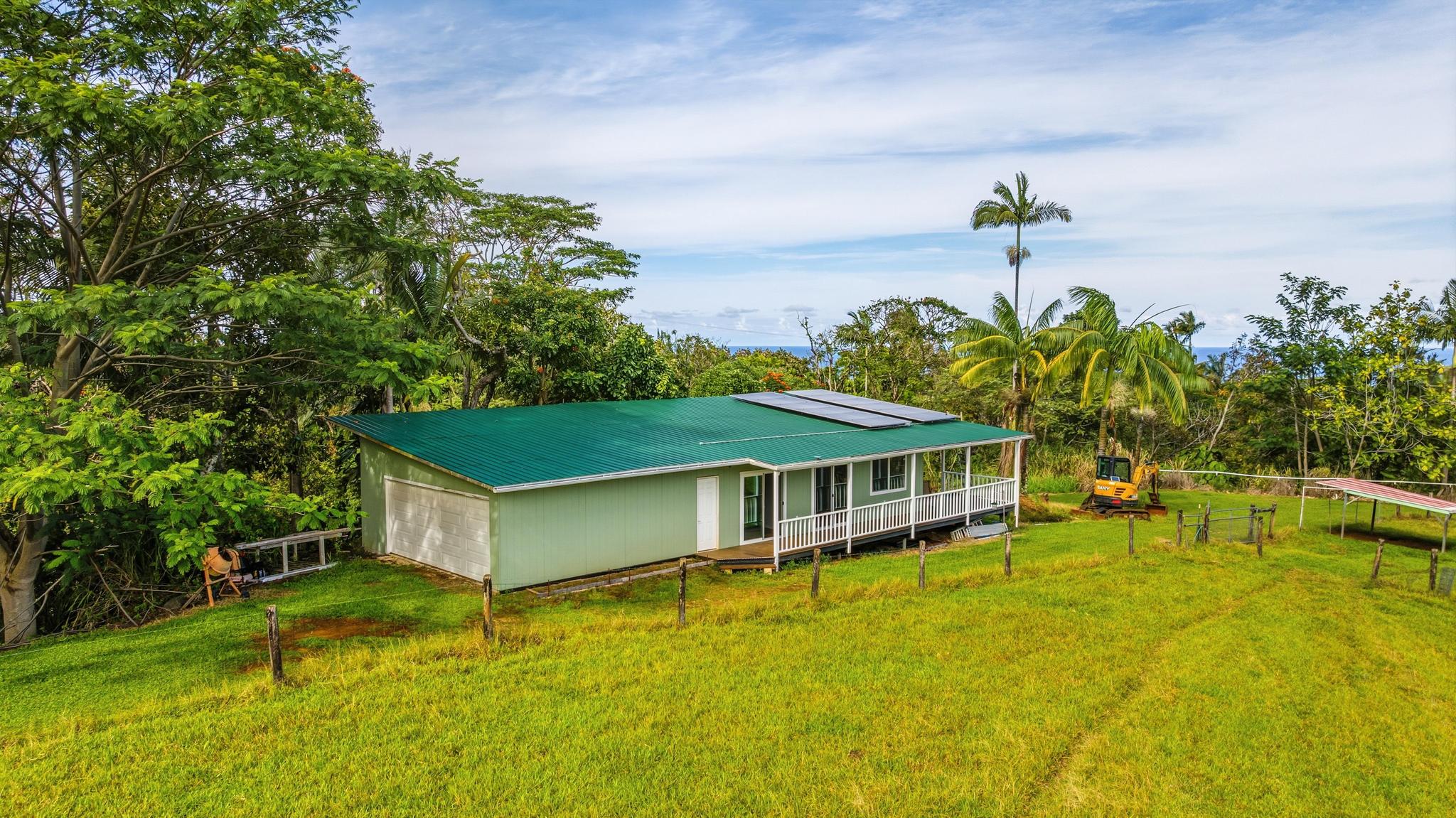 7 Iliopua Road Honomu, HI 96728 - Photo 5 of 30 a white house with a large pool and lawn chairs under an umbrella