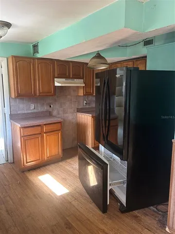 a kitchen with stainless steel appliances granite countertop a refrigerator a sink and wooden cabinets