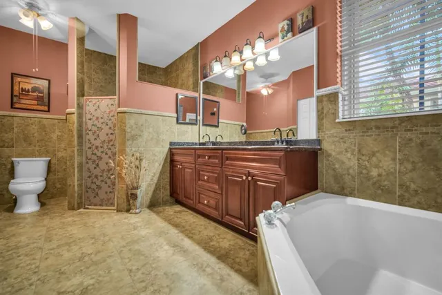 a spacious bathroom with a granite countertop sink a toilet and a bathtub