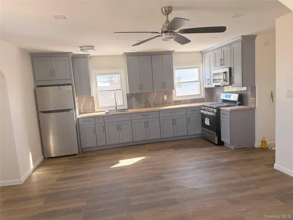 a kitchen with stainless steel appliances granite countertop a refrigerator a sink dishwasher a stove top oven a refrigerator and cabinets