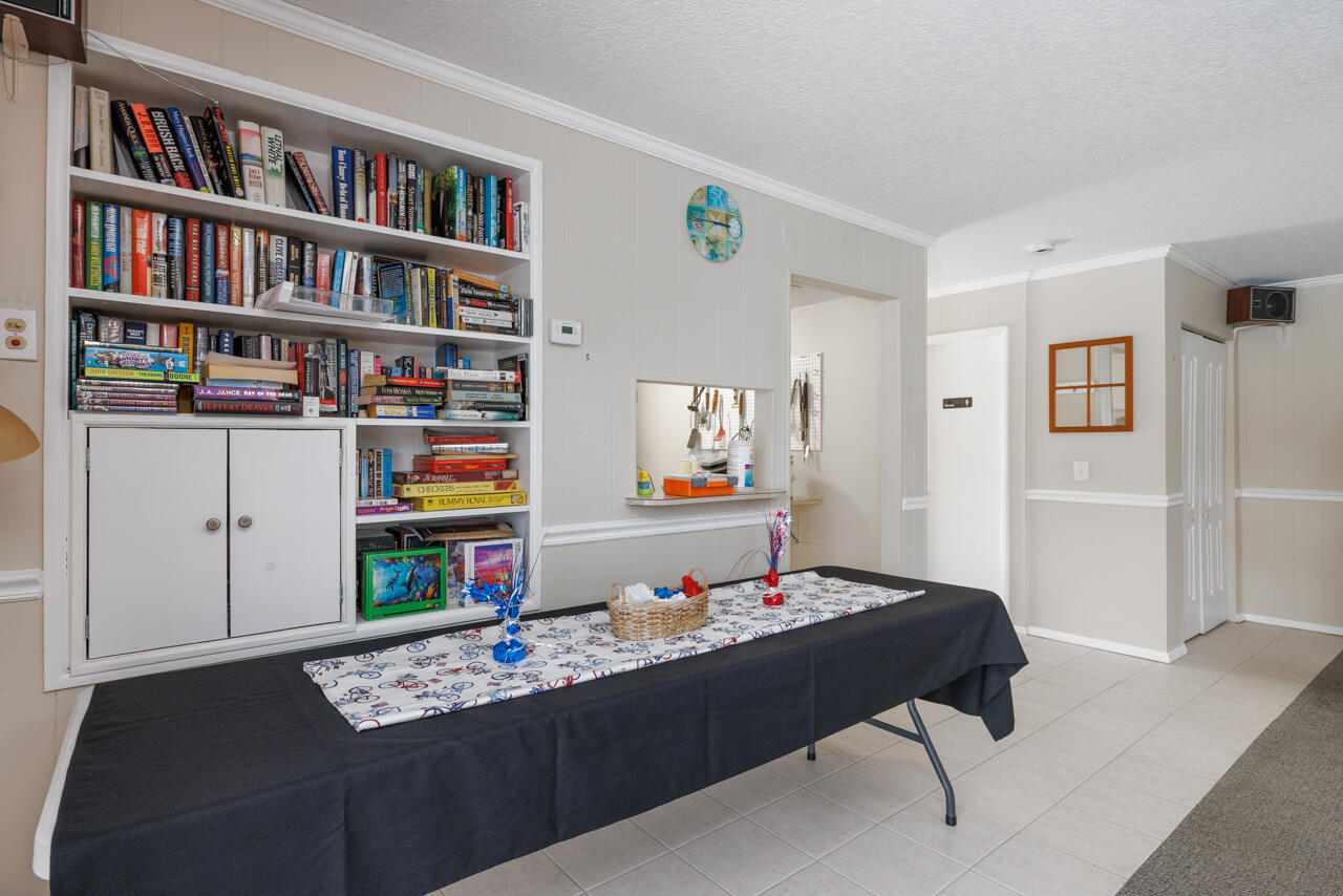 2950 Southeast Ocean Boulevard, Unit 533 Stuart, FL 34996 - Photo 29 of 34 a living room with lots of furniture and a book shelf