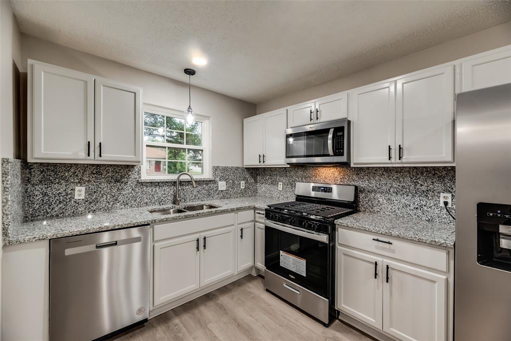 a kitchen with granite countertop white cabinets white stainless steel appliances and sink