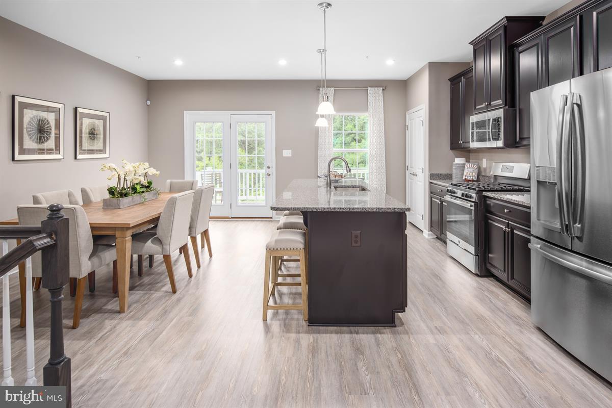 3203 Laurel Hill Road Hanover, MD 21076 - Photo 7 of 21 a kitchen with stainless steel appliances granite countertop a refrigerator a stove a sink a dining table and chairs with wooden floor