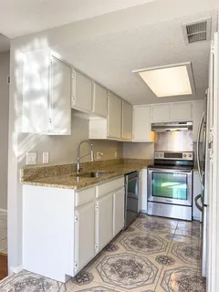 a kitchen with stainless steel appliances granite countertop a sink stove and cabinets