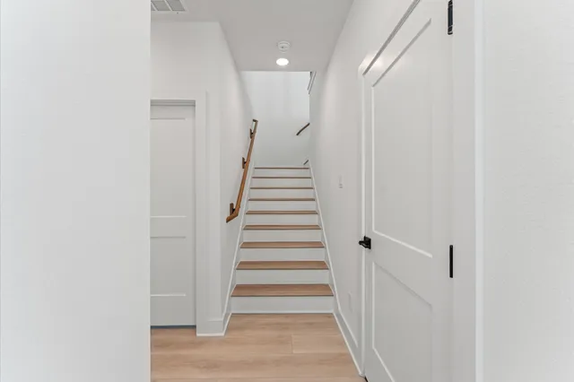 a view of a hallway with stairs and wooden floor