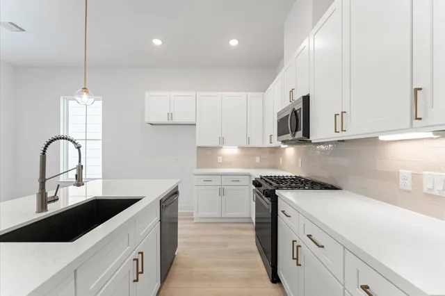 a kitchen with kitchen island granite countertop a sink a stove and cabinets