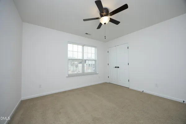 an empty room with a window and a fan