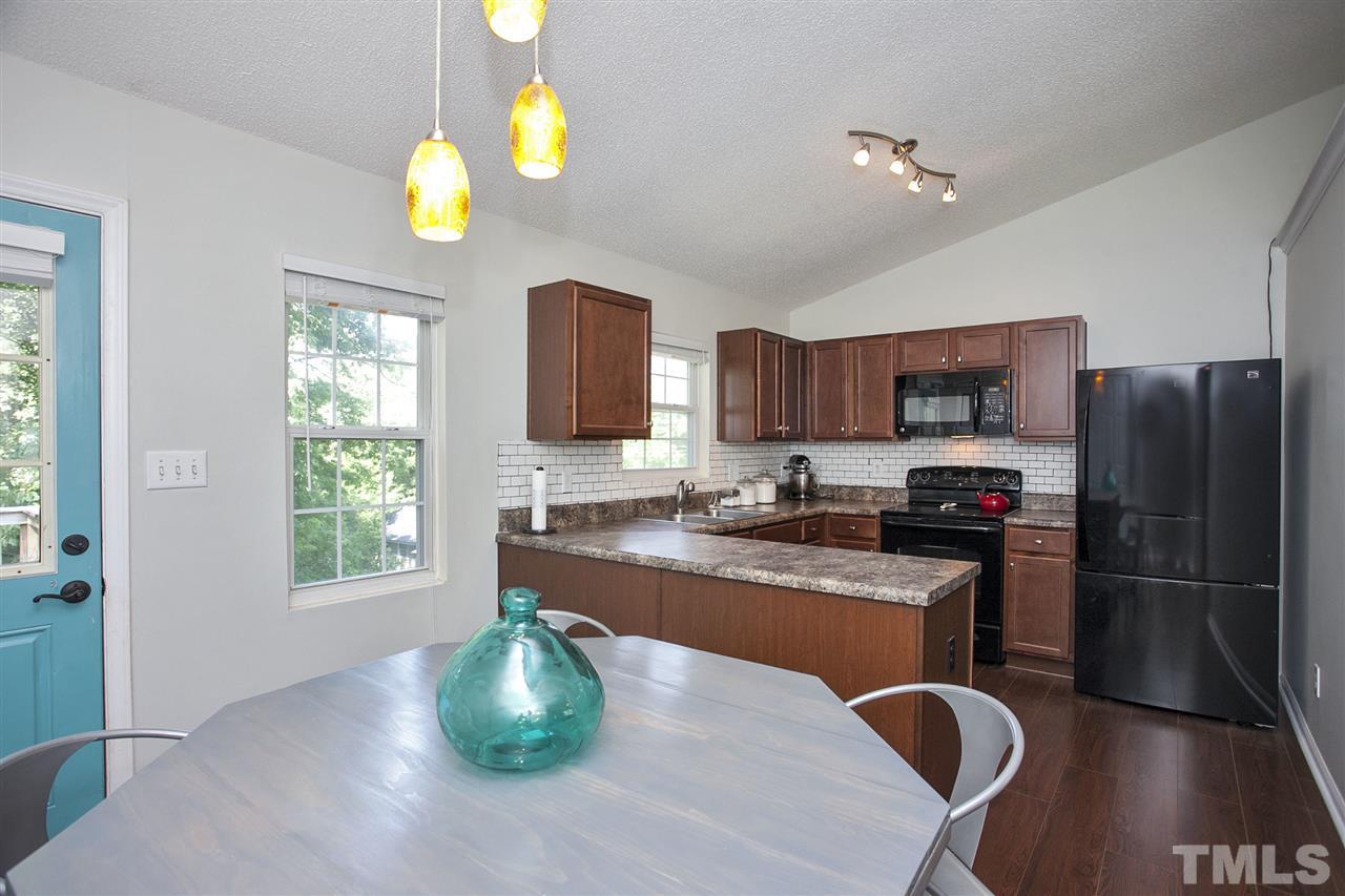 1145 Marlborough Road Raleigh, NC 27610 - Photo 5 of 17 a kitchen with stainless steel appliances granite countertop a refrigerator a stove top oven a sink dishwasher and white cabinets with wooden floor