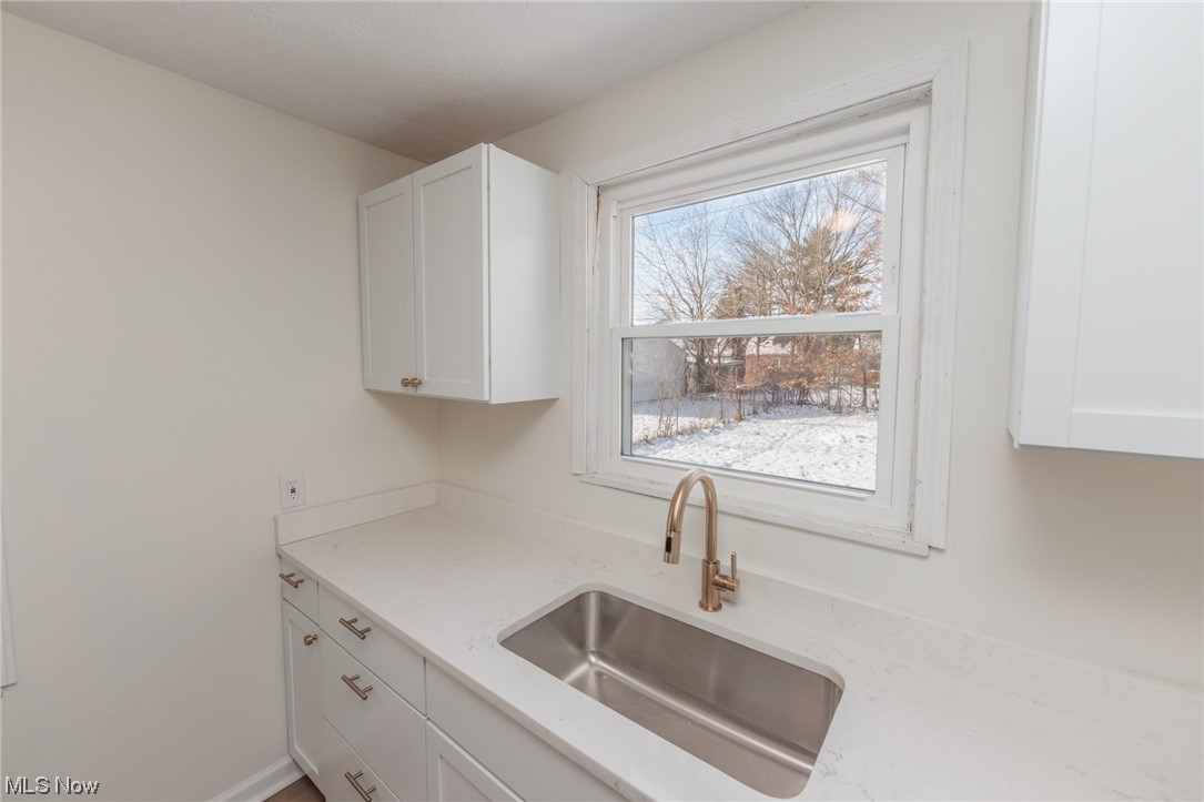 3880 Strandhill Road Cleveland, OH 44128 - Photo 16 of 33 Kitchen with sink, a wealth of natural light, white cabinetry, and light stone counters