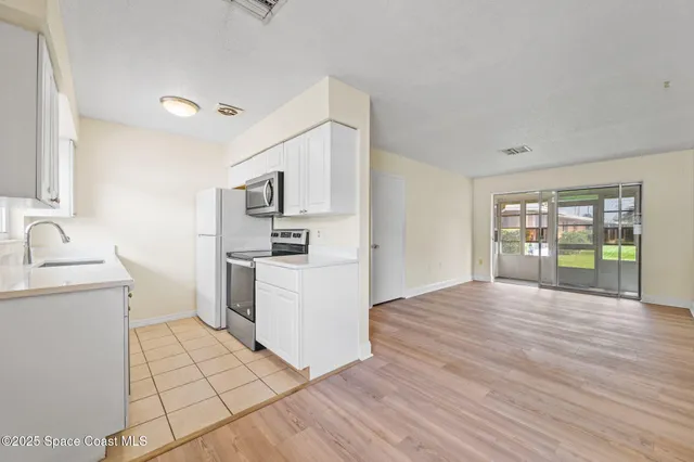 a view of a kitchen with white cabinets and wooden floor