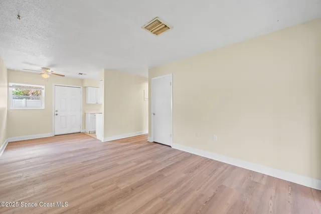 a view of an empty room with wooden floor and a window