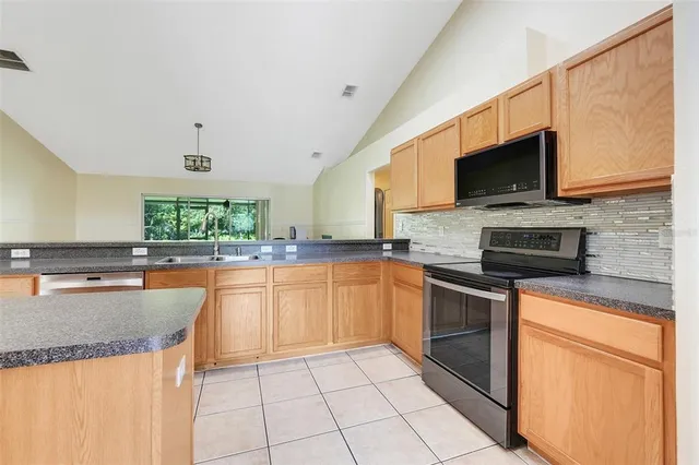 a kitchen with stainless steel appliances granite countertop a stove top oven a sink dishwasher a dining table and chairs with wooden floor