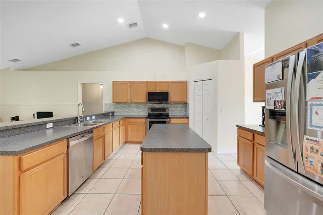 a large kitchen with stainless steel appliances granite countertop a stove a sink and a refrigerator