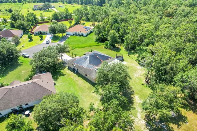 an aerial view of residential house with outdoor space and trees all around