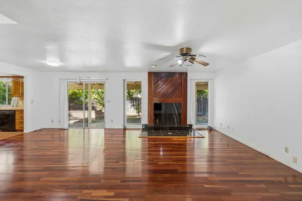 a view of an empty room with window and wooden floor