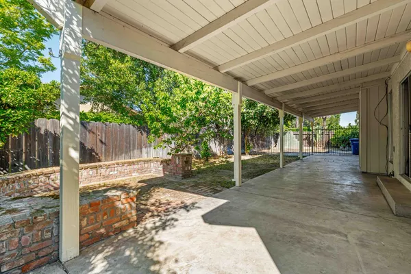 a view of a backyard with large trees and wooden fence