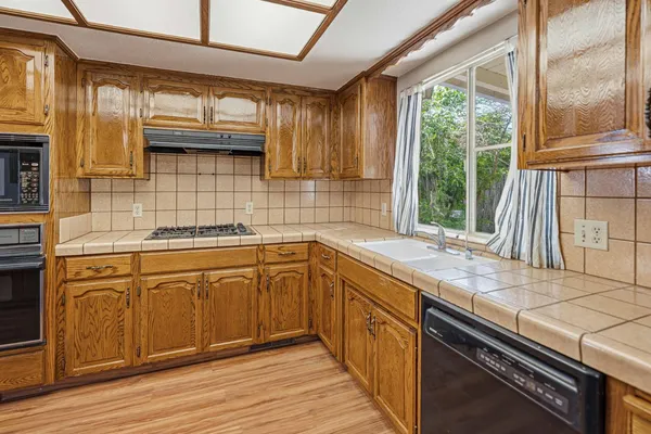a kitchen with stainless steel appliances granite countertop a sink a stove and a wooden cabinets