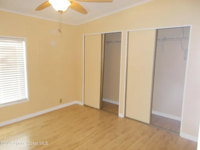 a view of an empty room with window and a ceiling fan