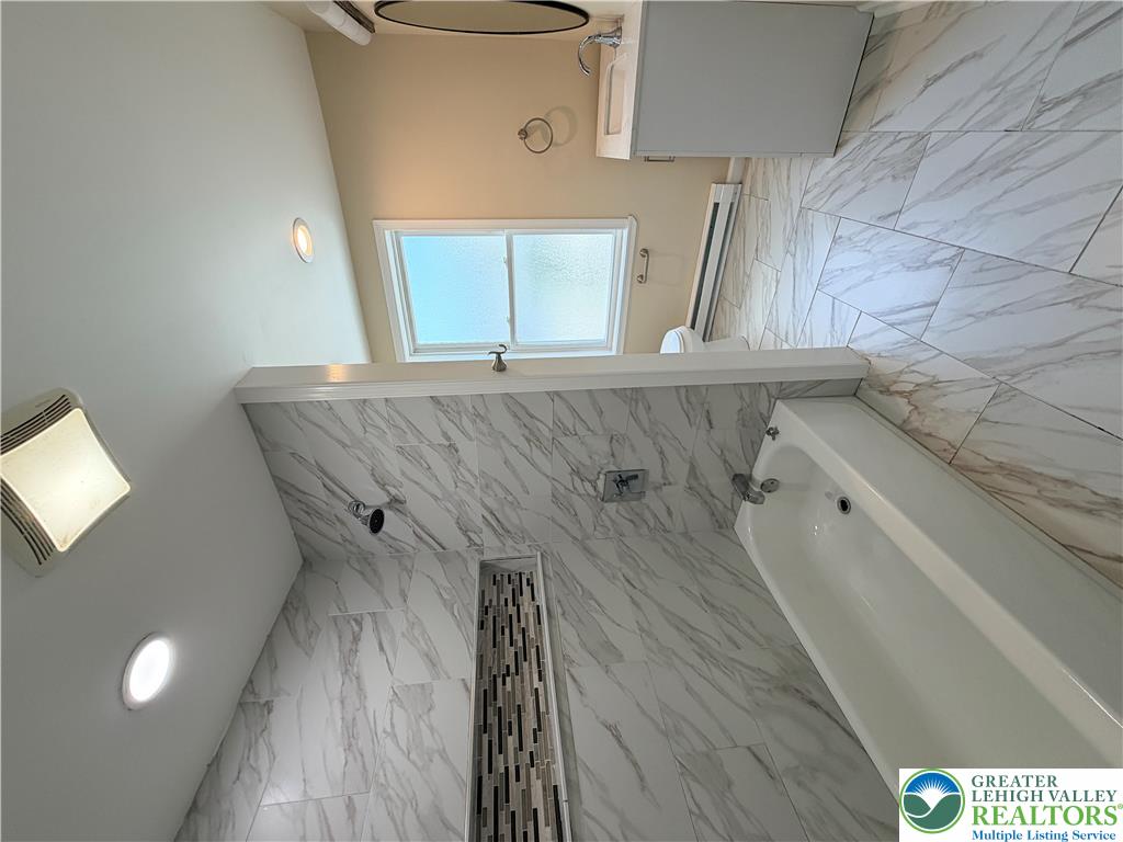 718 Ferry Street Easton, PA 18042 - Photo 20 of 37 Luxurious marble-patterned tile and a spacious soaking tub elevate this bath space.