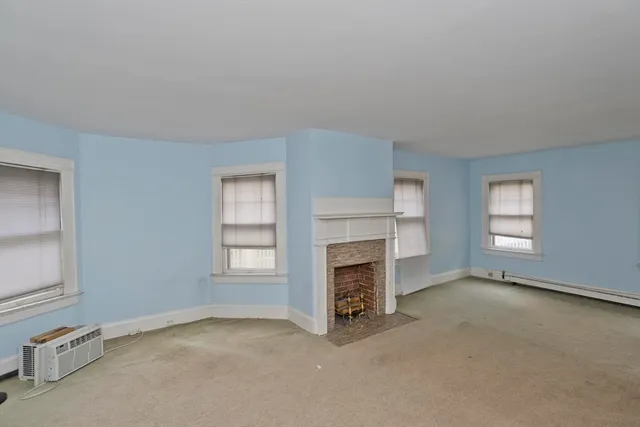 an empty room with windows and fireplace