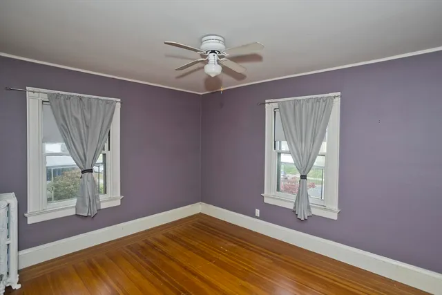 a view of empty room with window and wooden floor