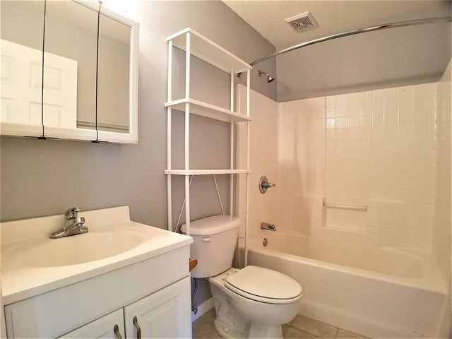an empty room with wooden floor chandelier fan and windows