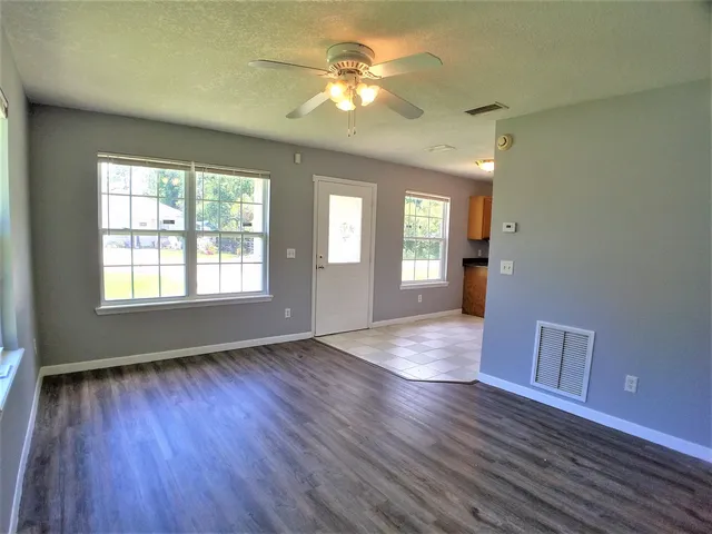 a view of an empty room with window and wooden floor