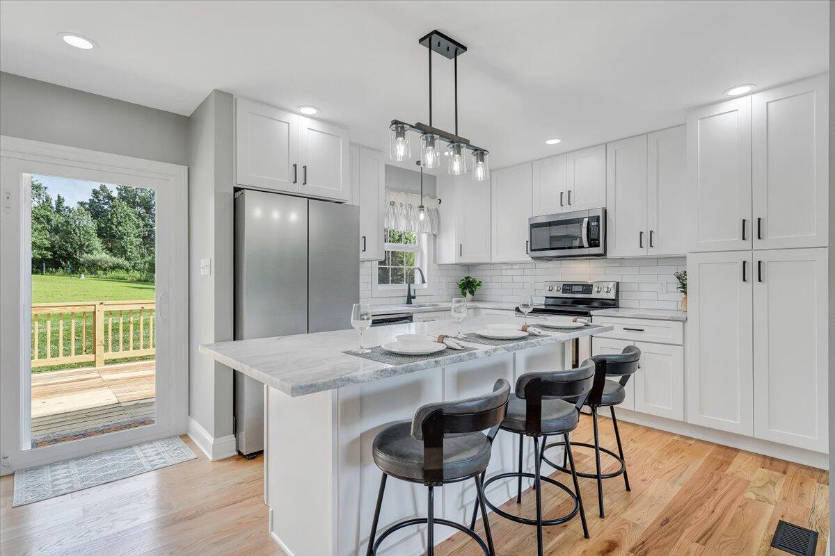 a kitchen with kitchen island granite countertop a center island a refrigerator cabinets and a dining table