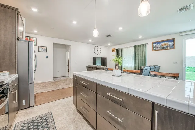 a kitchen with stainless steel appliances kitchen island granite countertop a table chairs sink and cabinets