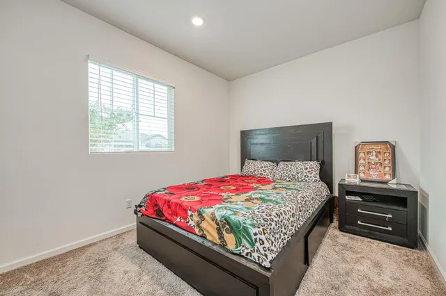 a bedroom with a bed and a lamp on dresser