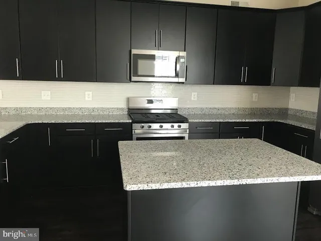 a kitchen with granite countertop a sink a stove and cabinets