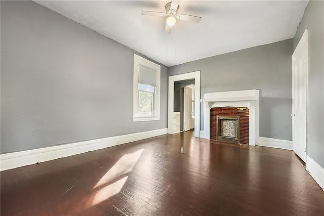 an empty room with wooden floor fireplace and windows