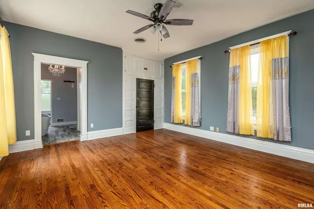 a view of an empty room with wooden floor and closet